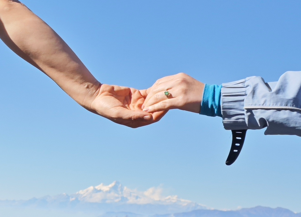 Hands reaching toward each other against Himalayan mountains and sky